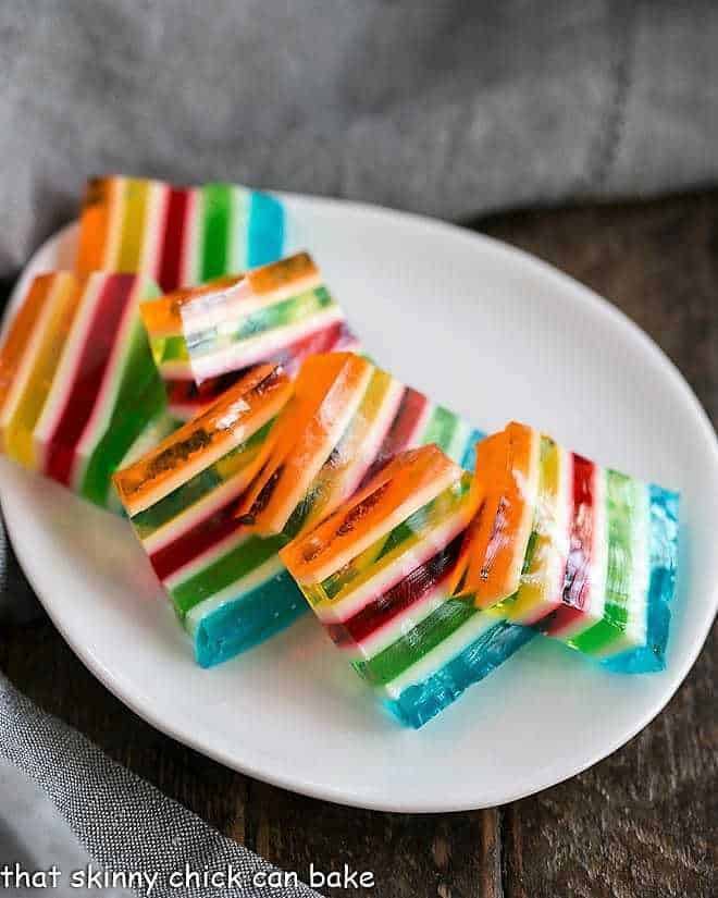 Slices of Layered Jello Rainbow Salad on a white oval dish.