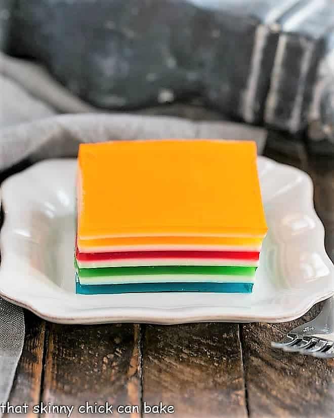 A square of Jello Rainbow Ribbon Salad on a square white plate.