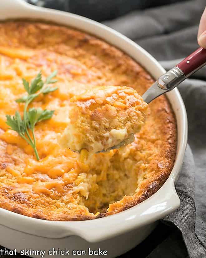 Spoonful of corn pudding recipe on a red handled serving spoon