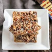 Toffee Caramel Magic Cookie Bars stacked on a white plate