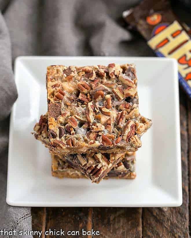 Toffee Caramel Magic Cookie Bars stacked on a white plate.