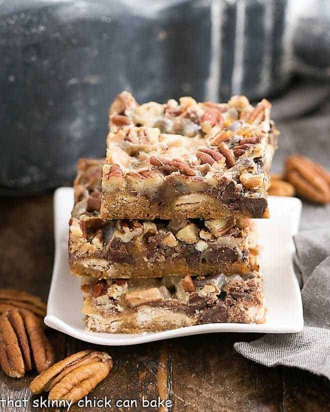 Toffee Caramel Magic Cookie Bars stacked on a rippled white plate