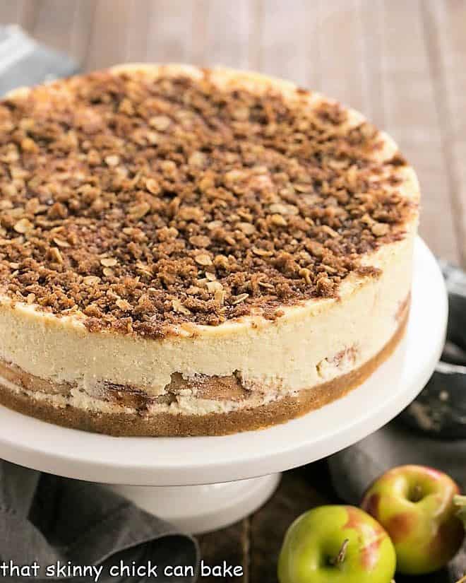 Whole Apple Crisp Cheesecake on a white cake stand