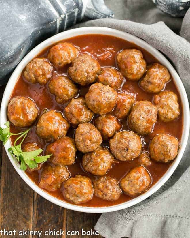 Overhead view of apricot glazed cocktail meatballs in a white serving bowl