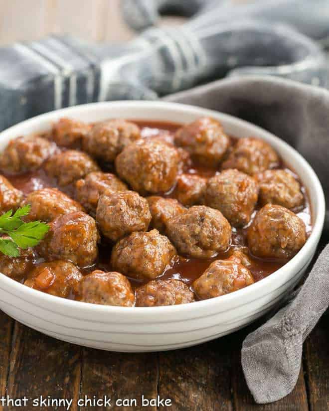 Apricot Glazed Cocktail Meatballs in a white ceramic bowl with a sprig of parsley