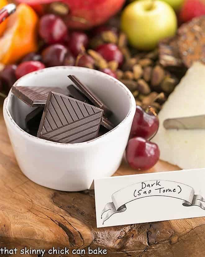 Chocolate squares in a white bowl with cherries and pistachios