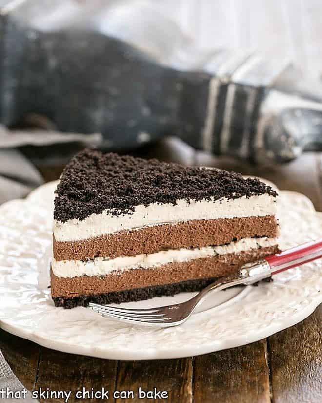 Slice of Layered Chocolate Cream Torte with a red handled fork on a white plate