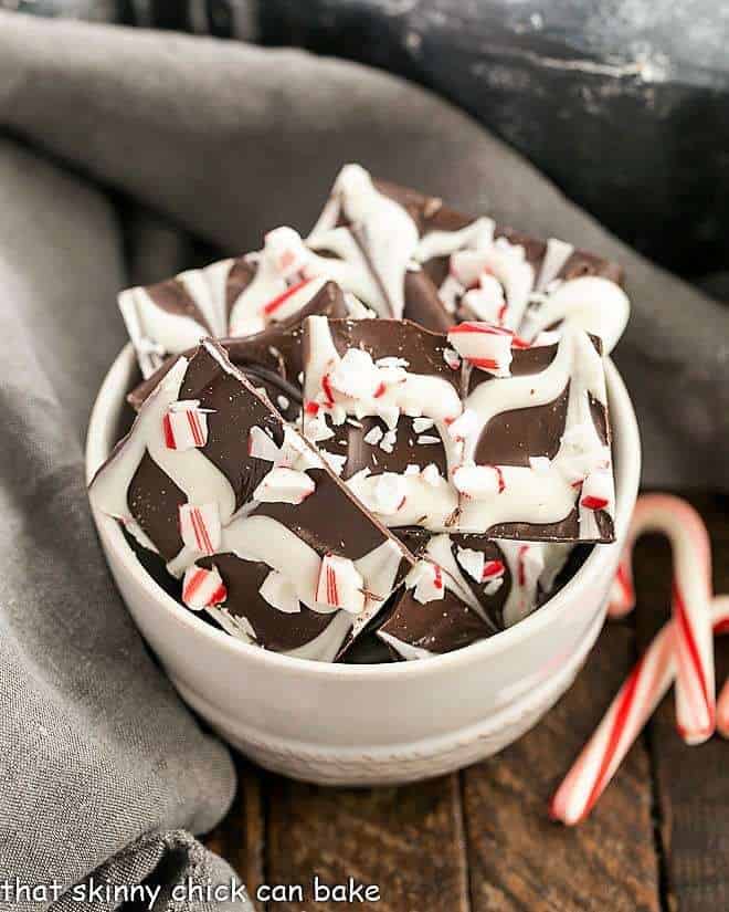 Swirled Peppermint Bark in a white bowl with candy canes.