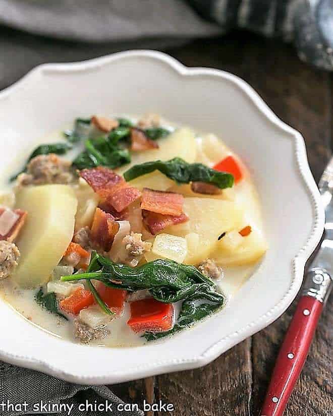 Zuppa Toscana or Tuscan Sausage Soup in a white, ruffle edged soup bowl.