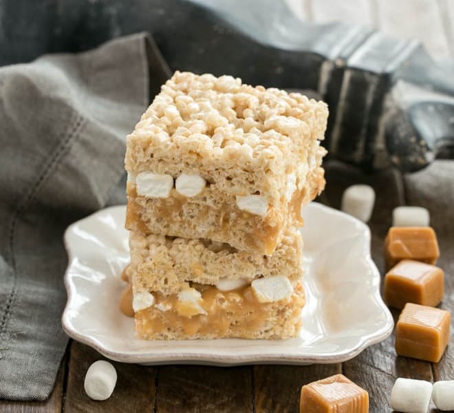 Caramel Stuffed Rice Krispie Treats stacked on a square plate.
