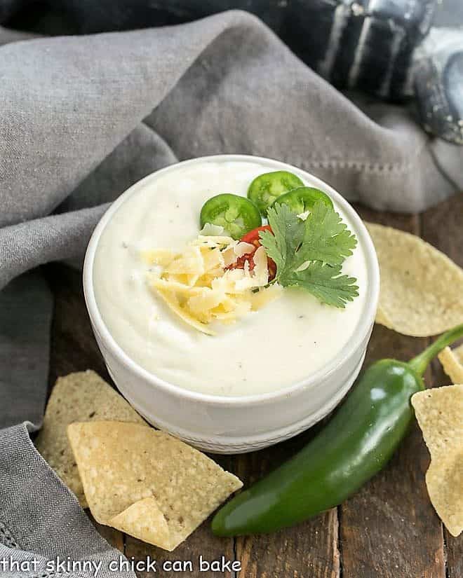 Small white bowl of Easy Homemade Queso Dip garnished with cheese and cilantro