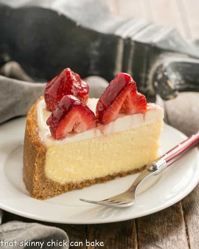 Strawberry Topped Cheesecake Slice on a white plate with a red handled fork