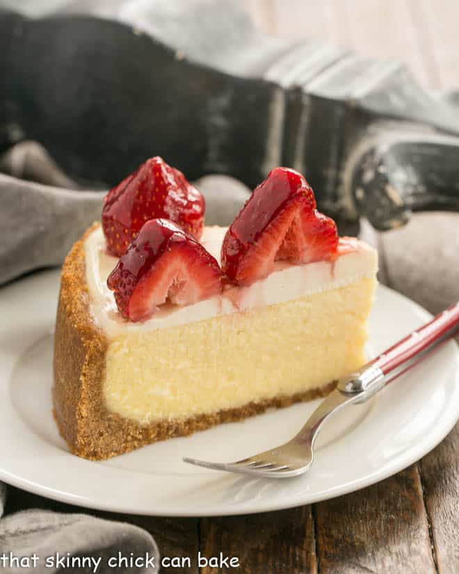 Strawberry Topped Cheesecake Slice on a white plate with a red handled fork.