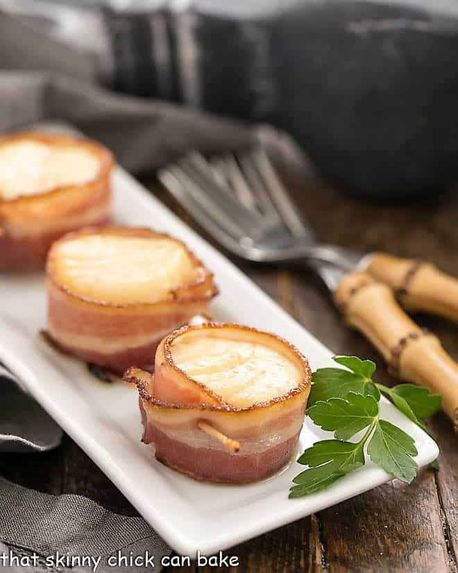 Bacon wrapped scallops on a white tray