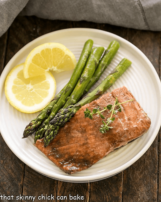 Overhead view of a salmon fillet with asparagus and lemons