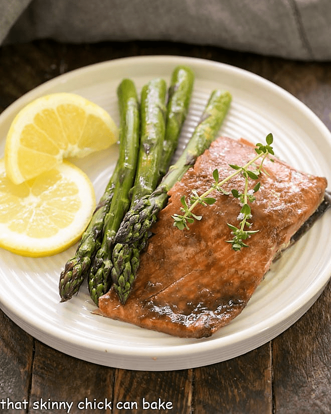 Salmon, asparagus and lemon slices on a white plate.