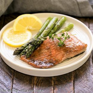 Easy Glazed Salmon on a white dinner plate with asparagus and lemons