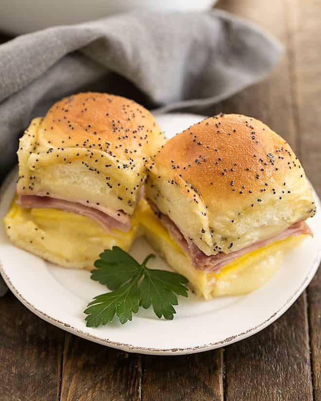 Ham, Egg and Cheese Breakfast Sliders on a small white plate with a sprig of parsley