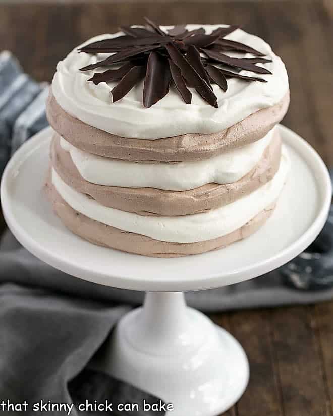 Side view of Layered Chocolate Meringue Cake on a white cake stand.