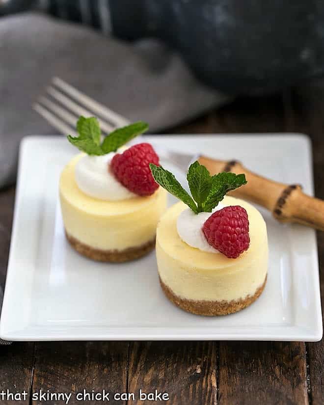 Mini Margarita Cheesecakes topped with raspberries on a square white plate.