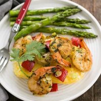 Cheesy Shrimp and Grits Casserole on a white dinner plate with asparagus
