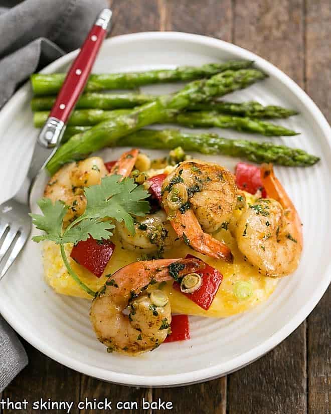 Cheesy Shrimp and Grits Casserole on a white dinner plate with asparagus