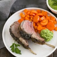 Herb Crusted Rack of Lamb with carrots and parsley pesto on a white dinner plate