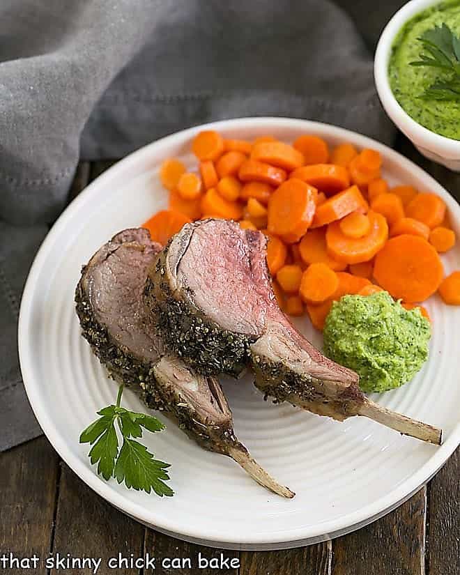 Herb Crusted Rack of Lamb with carrots and parsley pesto on a white dinner plate