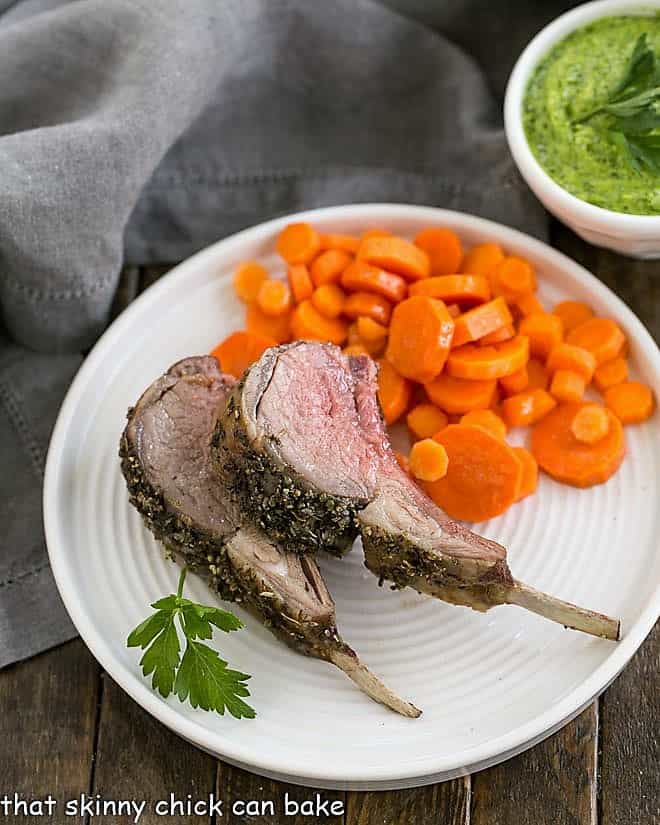 Herb Crusted Rack of Lamb slices on a white plate with carrot coins.