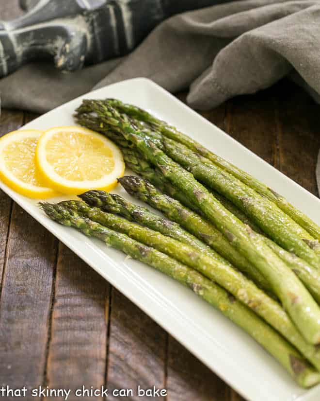 Easy Oven Roasted Asparagus on a white tray with lemon slices to garnish