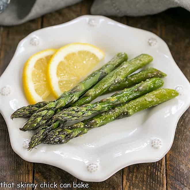 Overhead view of Easy Oven Roasted Asparagus on a white plate with lemon slices