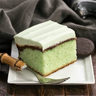 A slice of creme de menthe cake on a white plate with a bamboo handle fork