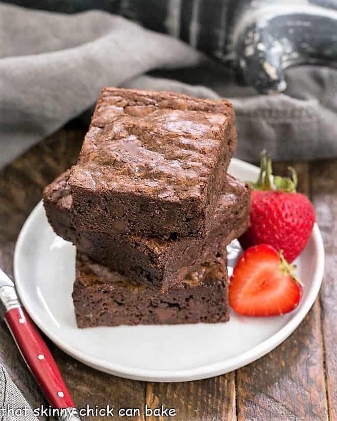 A stack of 3 homemade sheet pan brownies on a small white plate