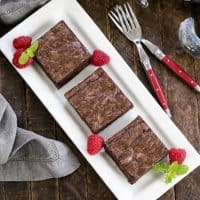 3 sheet pan brownies on a white tray with raspberries and mint