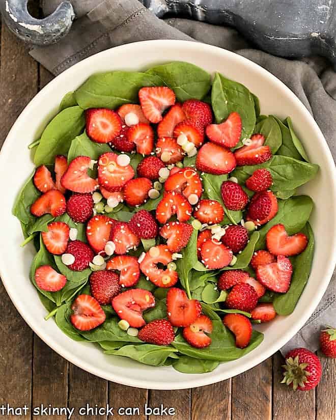 Overhead view of an easy strawberry spinach salad in a white ceramic bowl