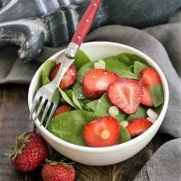 Strawberry spinach salad in a salad bowl with a red handled fork