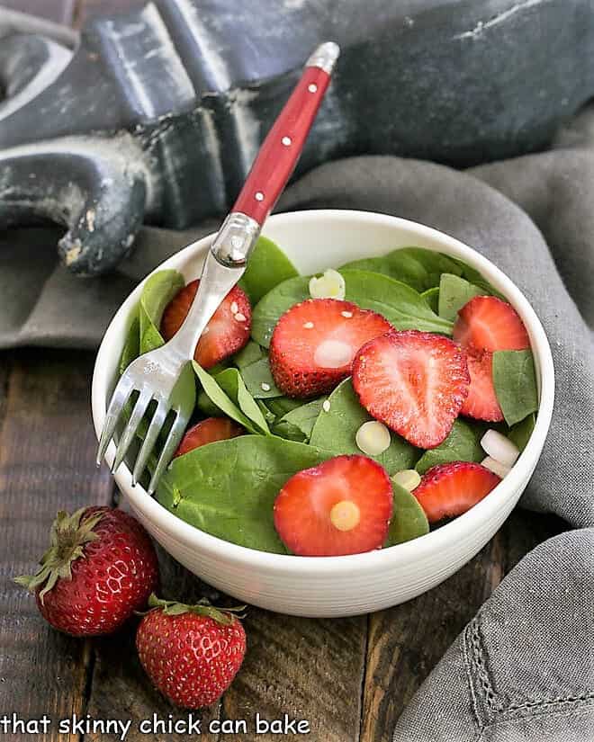 Strawberry spinach salad in a salad bowl with a red handled fork