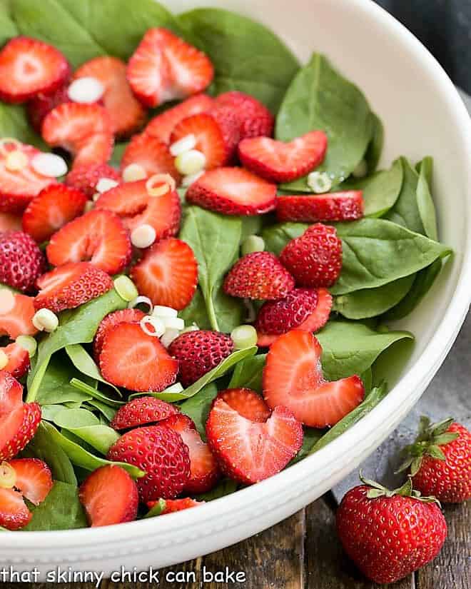 Undressed Strawberry Spinach Salad in a white serving bowl