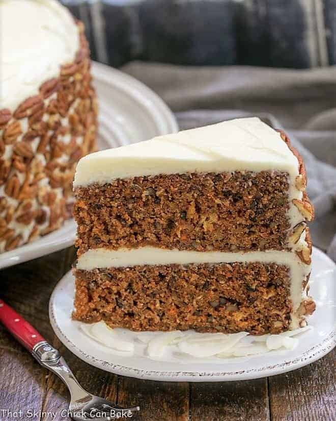 Moist Carrot Cake Recipe with Pineapple, Coconut and Pecans - Dense, delicious and loaded with flavor and texture, then topped with decadent cream cheese frosting Slice of Classic Carrot Cake on a white dessert plate.