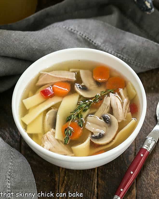 Bowl of Homemade Chicken Stock with carrots, noodles and chicken.