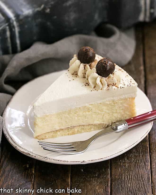Slice of Tiramisu Cheesecake on a dessert plate with a red handled fork