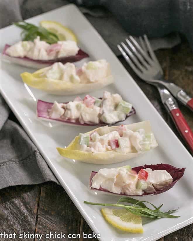 Lobster Salad in Endive Cups on a white tray with red handled forks