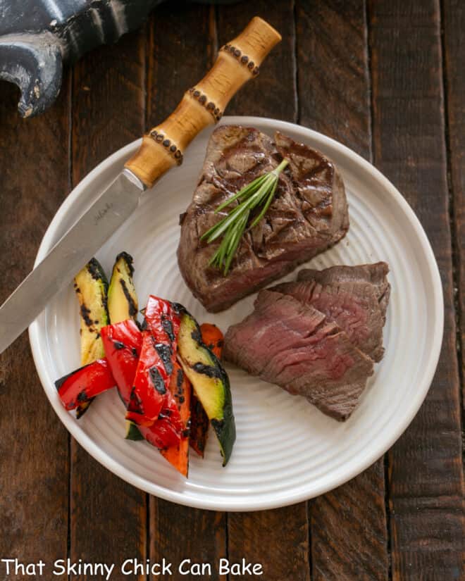 Sliced Filet with Red Wine Balsamic Sauce  on a white plate with a knife and veggies