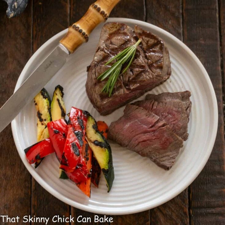 Overhead view of partially sliced filet mignon on a white plate.