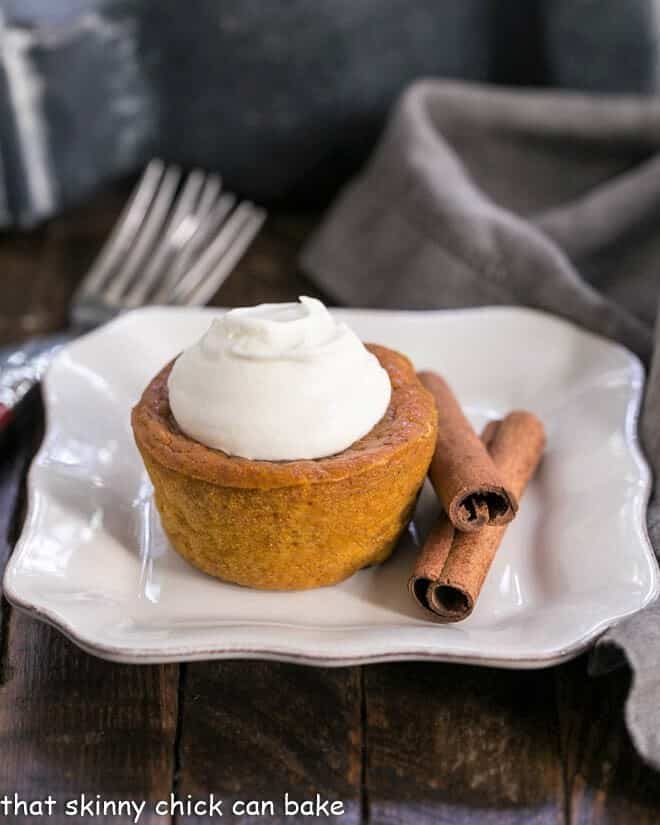 Pumpkin Pie Cupcake on a square white plate topped with a dollop of whipped cream.