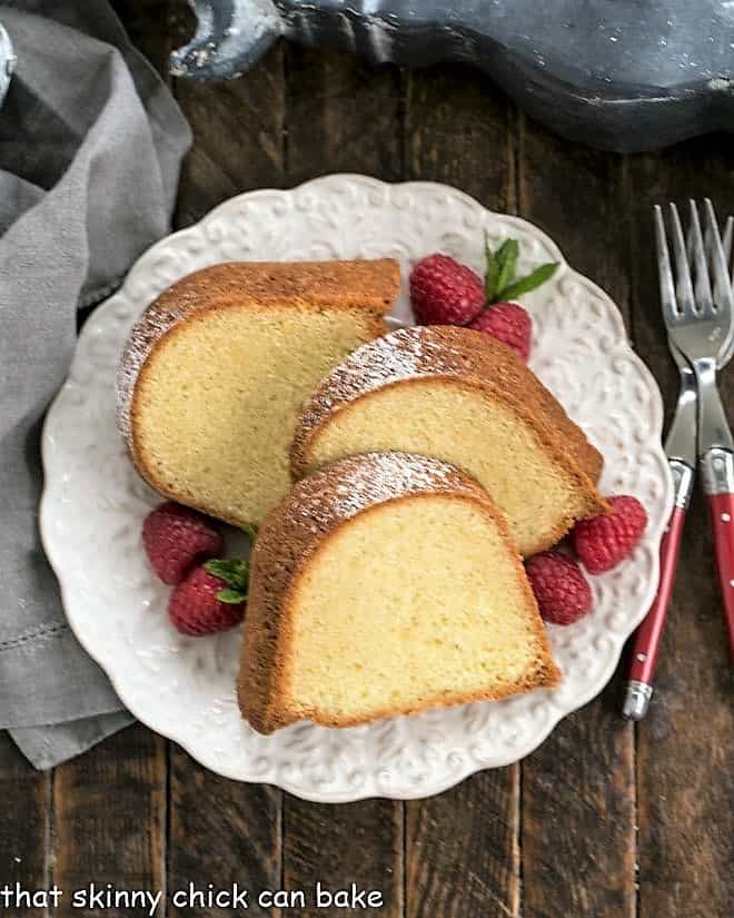 Overhead view of Sour Cream Pound Cake on a white serving plate with raspberries and mint to garnish