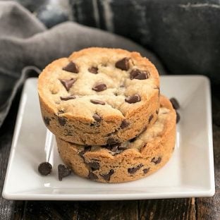 Two Chocolate Chip Cookie Bars stacked on a square white plate