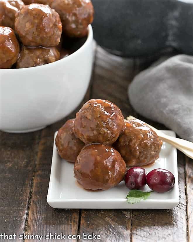 Baked Meatballs on an appetizer plate with a sprig of parsley and a couple fresh cranberries