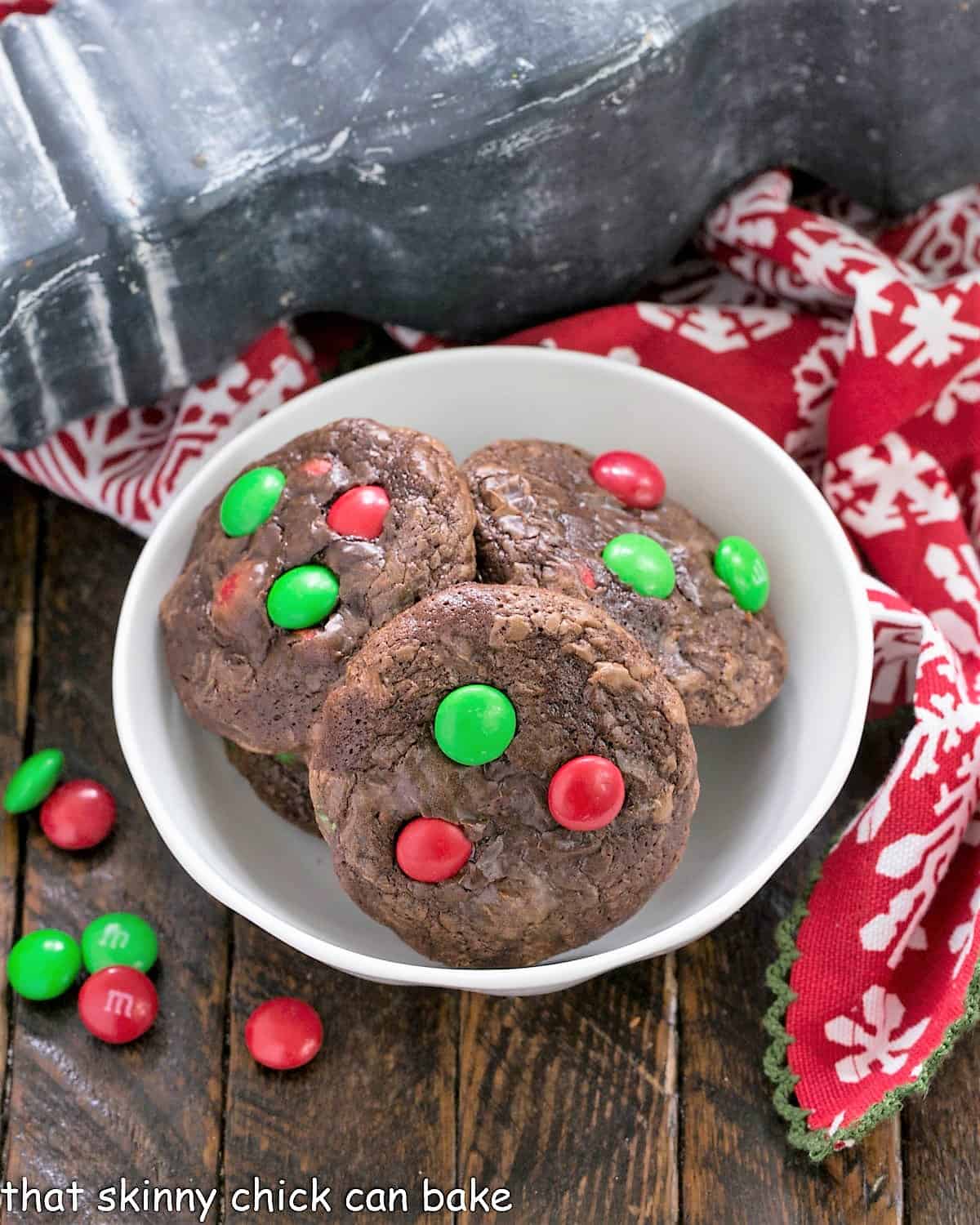 Overhead view of truffle cookies in a small white bowl  next to a red holiday napkin.