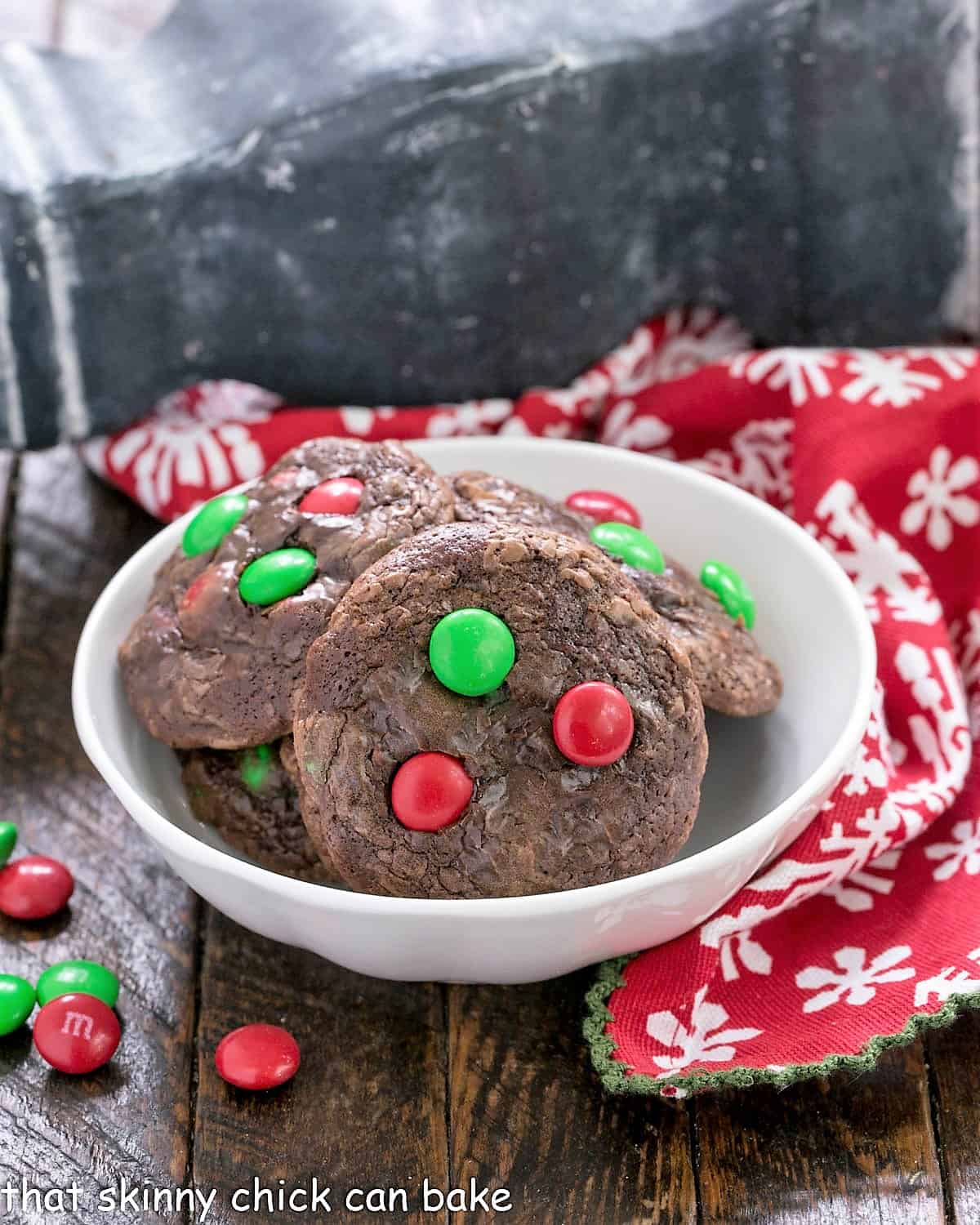 Holiday truffle cookies in a small white bowl surrounded by holiday M&Ms.
